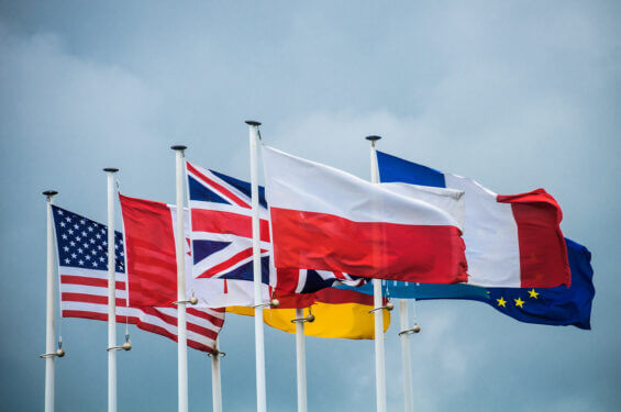 Flags of the United States, Canada, Great Britain, Germany, France, Poland and the European Union fly over a World War II monument in Normandy, France.