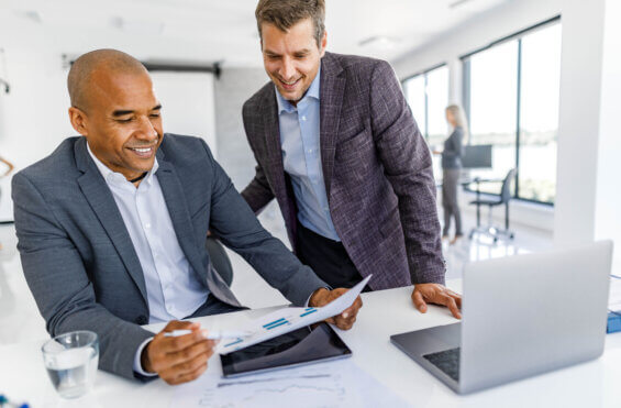 Happy African American businessman and his colleague cooperating while reading paperwork in the office.