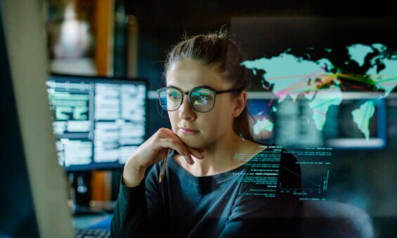 A woman with glasses works at her desktop computer.