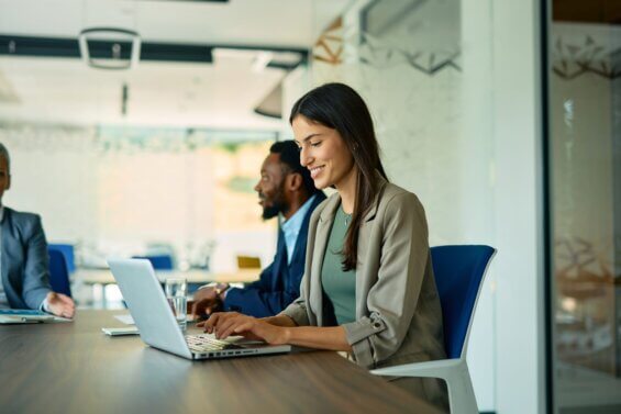 A business woman smiles while using her laptop.