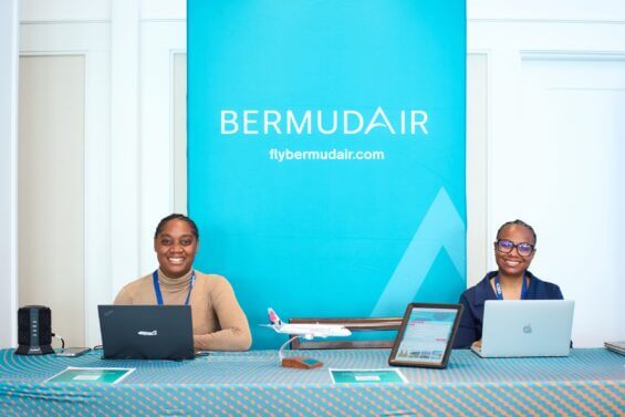 Two women at an event booth for Bermuda Air smile at the camera.