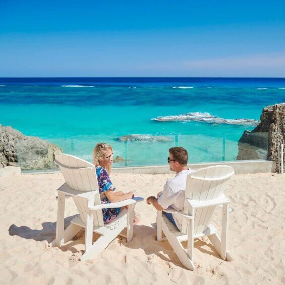 A couple sits in beach chairs on a beautiful shoreline in Bermuda.