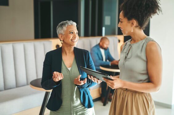 Two business women speak to each other in an office.