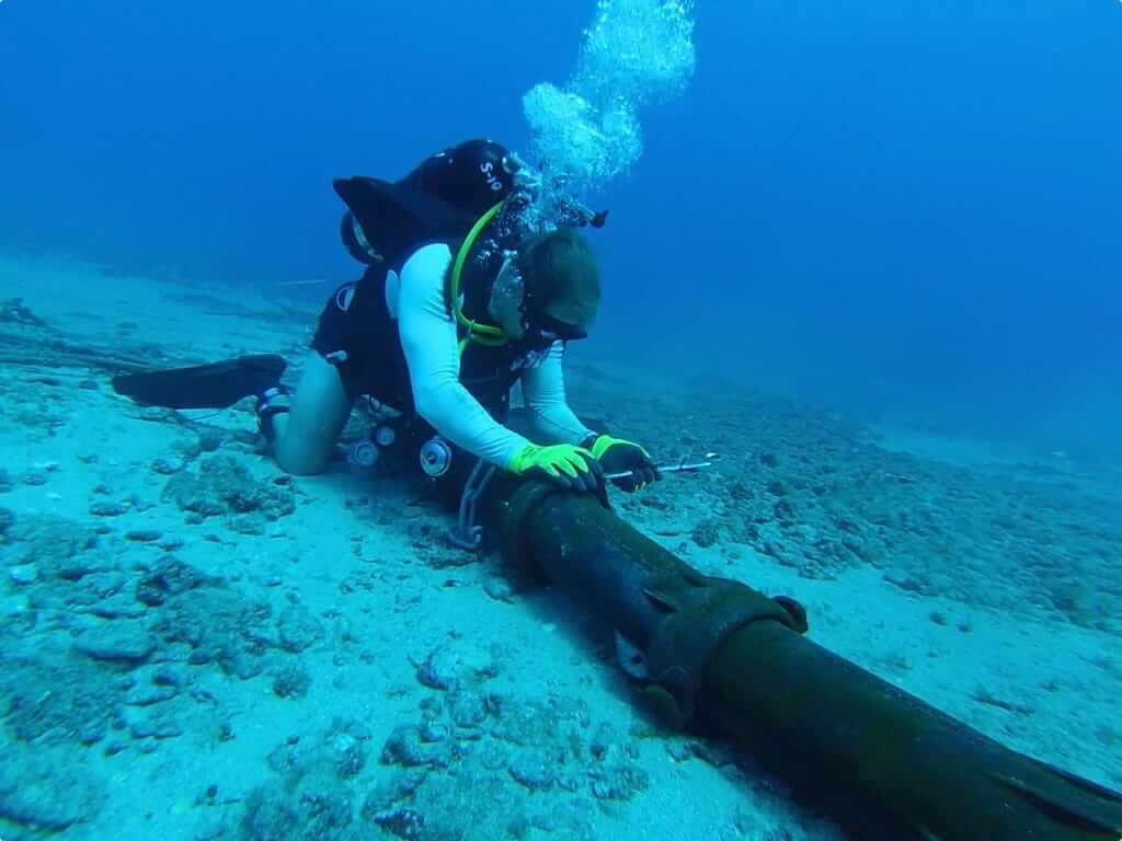 An underwater diver performs work on a subsea cable.