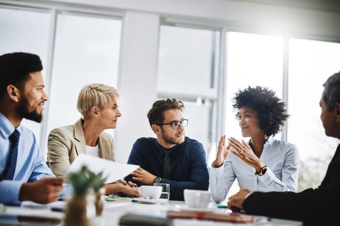 A group of young professionals sit at a table during a business meeting.